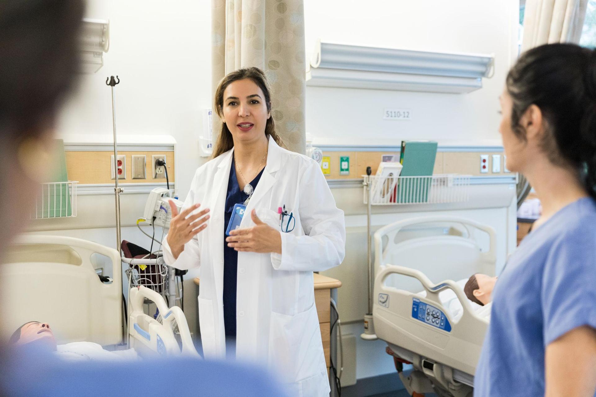 Doctor guiding students during clinical training in a simulated hospital ward